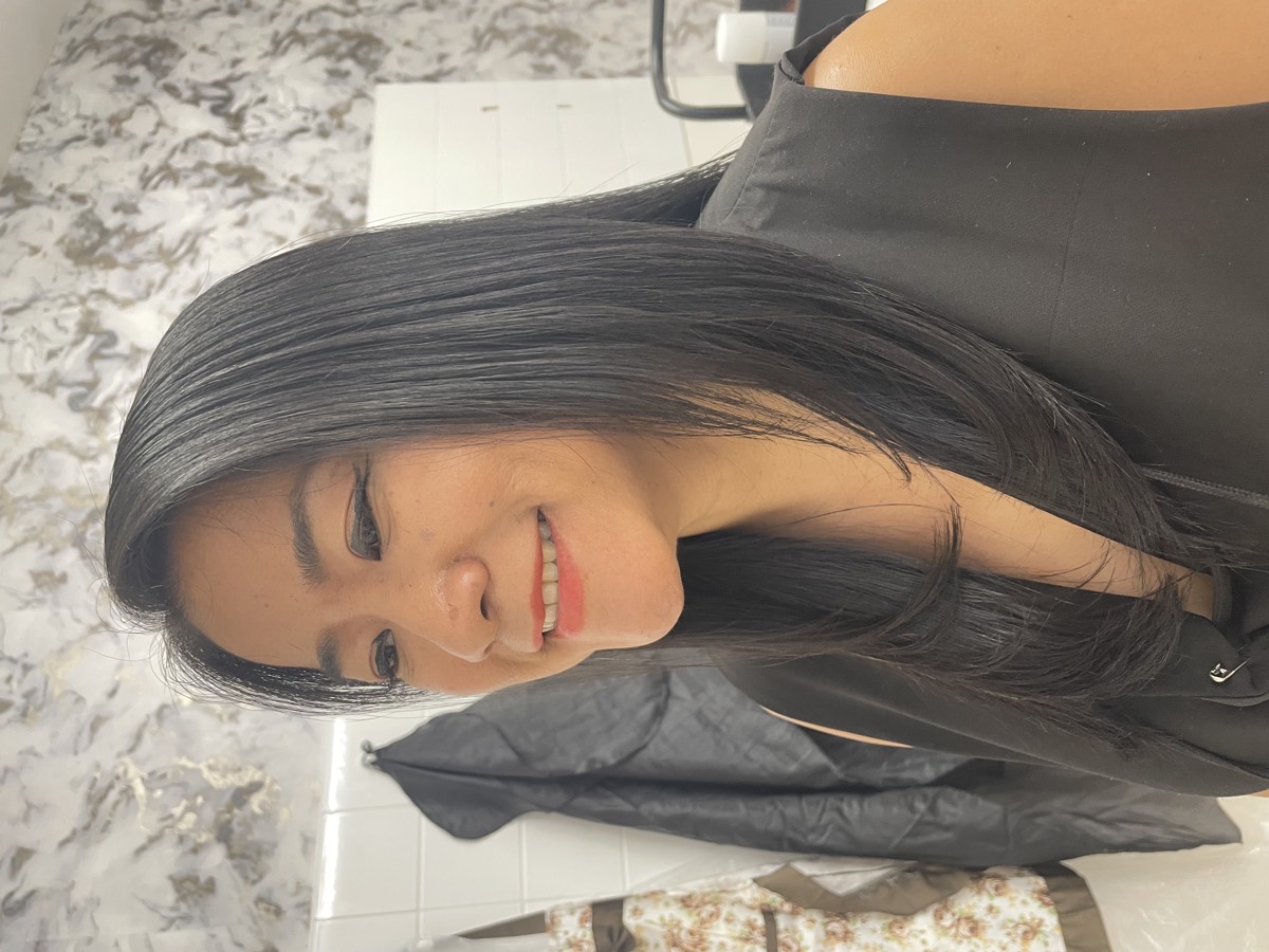 Client smiling after a cut and finish, hair straight and glossy
